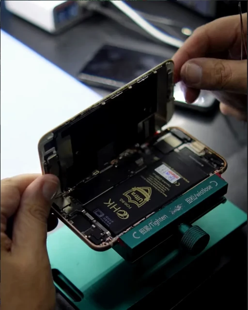 Técnico da Rede Celltronics abrindo um celular na bancada, com a bateria e a placa do aparelho à mostra