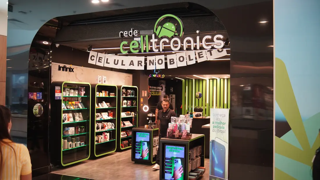 Fachada de uma loja da Rede Celltronics em shopping, com totens de assistência técnica