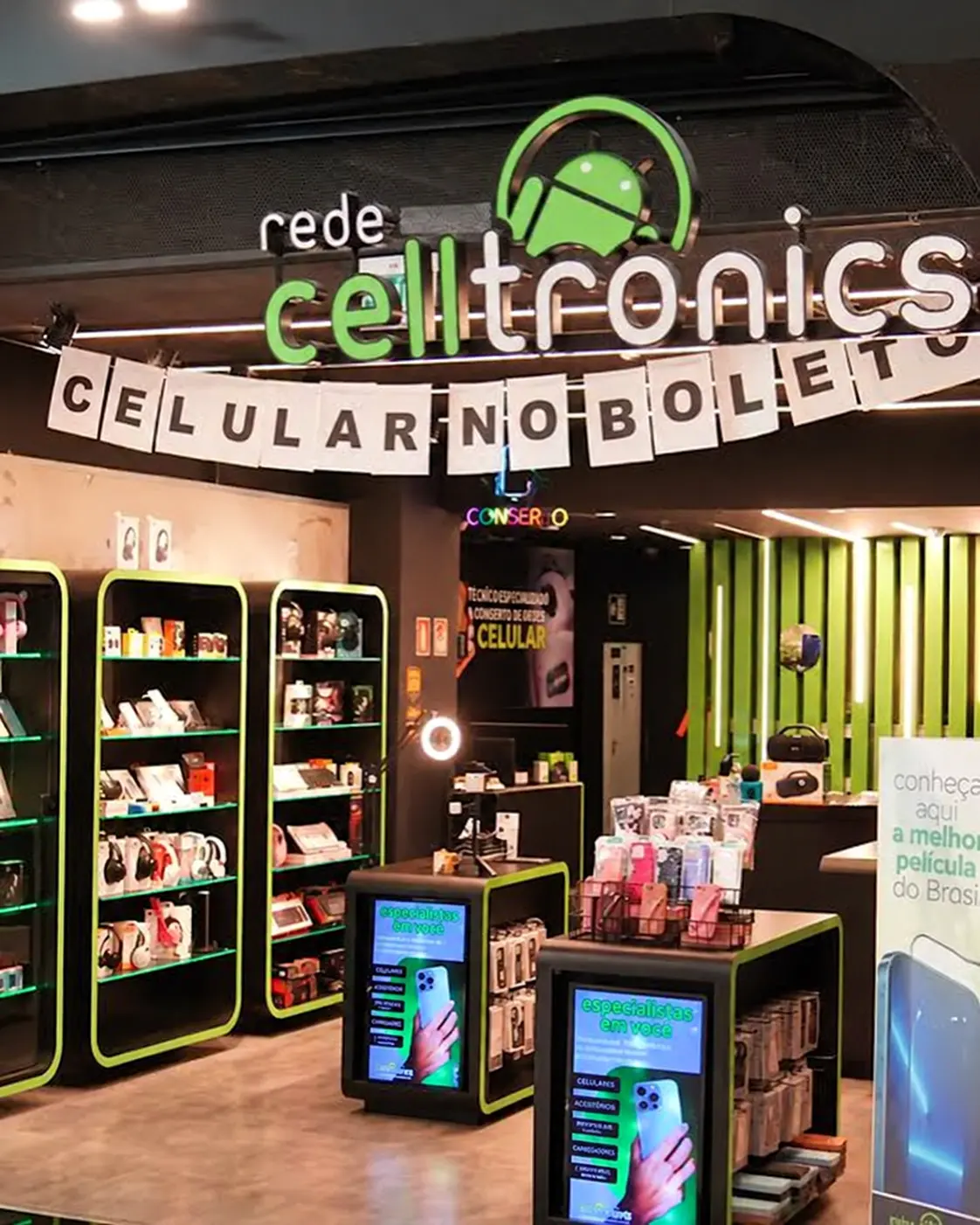 Loja da Rede Celltronics em shopping, com placa de conserto e o aviso de técnico especializado em conserto de celular